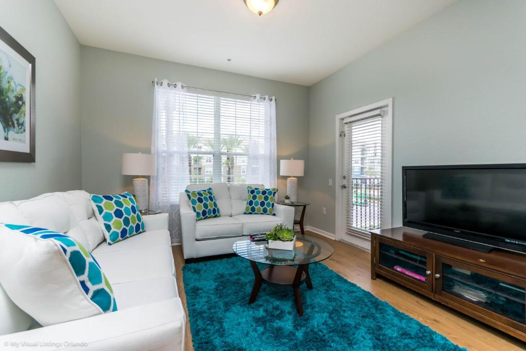 ein Wohnzimmer mit weißen Möbeln und einem Flachbild-TV in der Unterkunft Spacious Condo Near Convention Ctr & I-Drive, Pool in Orlando