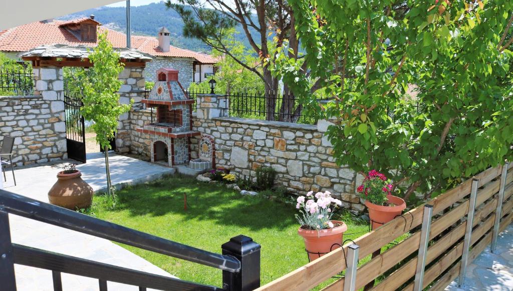 un patio trasero con una pared de piedra y un jardín con chimenea. en Kassiani House, en Theológos
