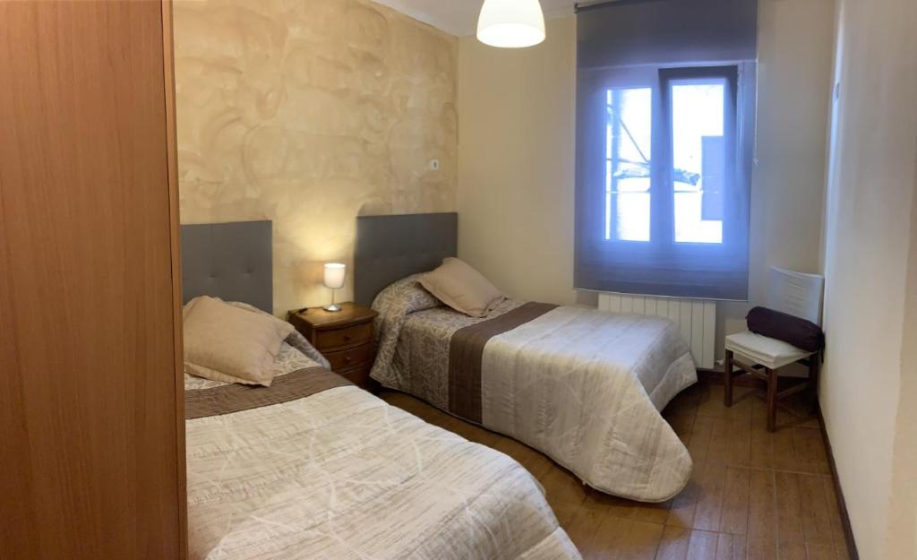1 dormitorio con 2 camas y ventana en Apartamento La Herradura, en Villarcayo