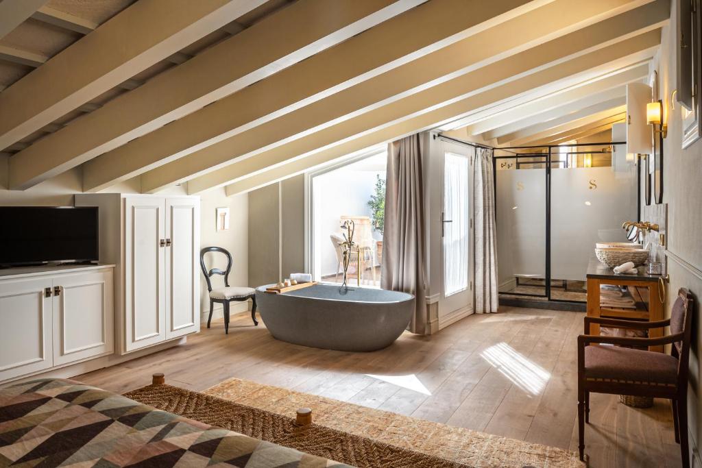 een grote badkamer met een bad en een raam bij Hotel Boutique Can Sastre in Ciutadella