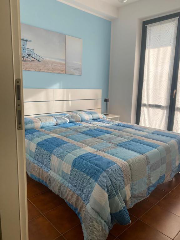 a bedroom with a bed with a blue and white blanket at A casa di Nonna Maria in Marcelli