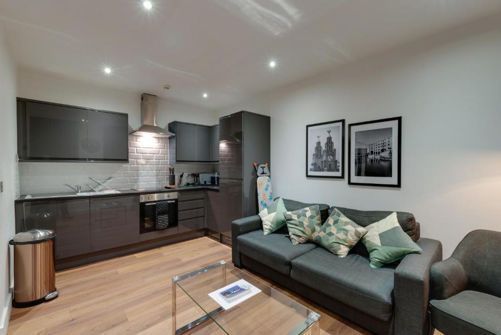 ein Wohnzimmer mit einem Sofa und einer Küche in der Unterkunft Lord Street Apartments By Happy Days in Liverpool