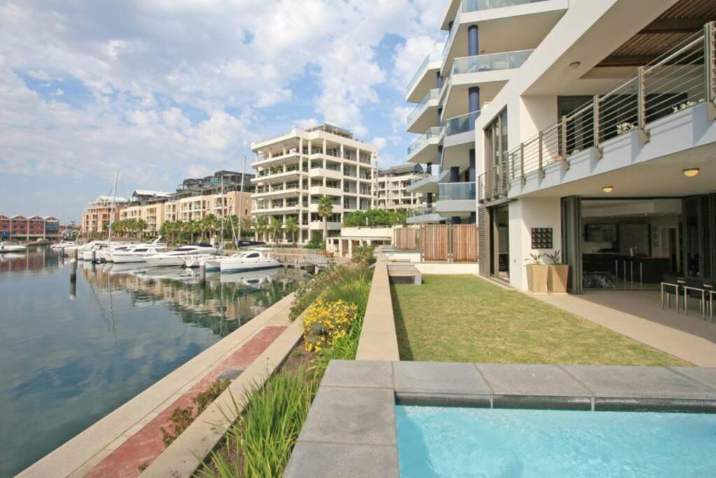 a house with a swimming pool next to a river at Outstanding V&A Marina Waterfront apartment in Cape Town