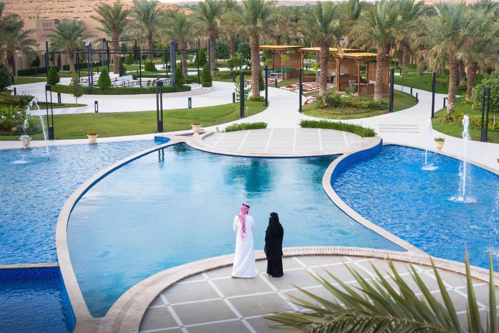 a bride and groom standing in front of a swimming pool at Dorat Najd Resort in Riyadh