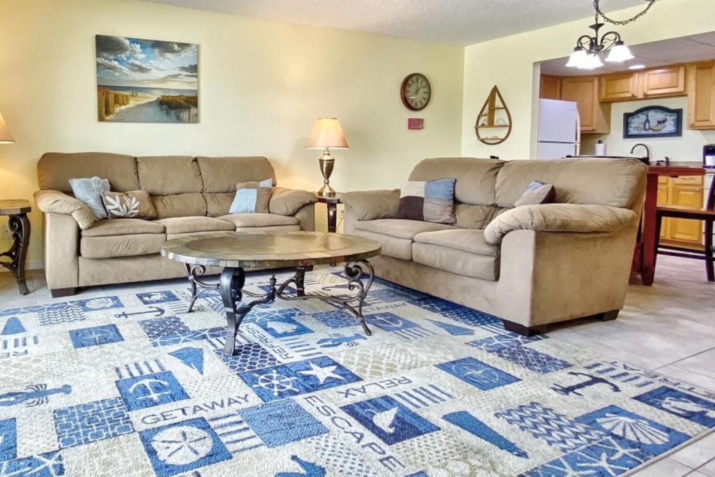 a living room with two couches and a table at Sea Breeze 705 in St Pete Beach
