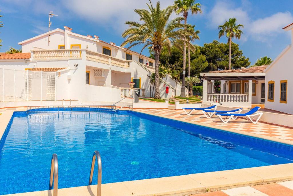 una piscina frente a una casa con palmeras en Apartamento Bon Repos A7, en Cala'n Bosch