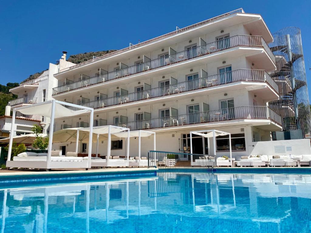 un hôtel avec une piscine en face d'un bâtiment dans l'établissement Hotel Nereida, à L'Estartit