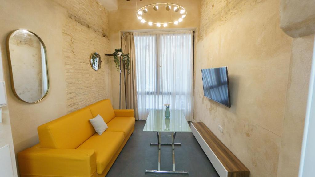 salon z żółtą kanapą i szklanym stołem w obiekcie RentalSevilla Cardenal Cervantes I w Sewilli