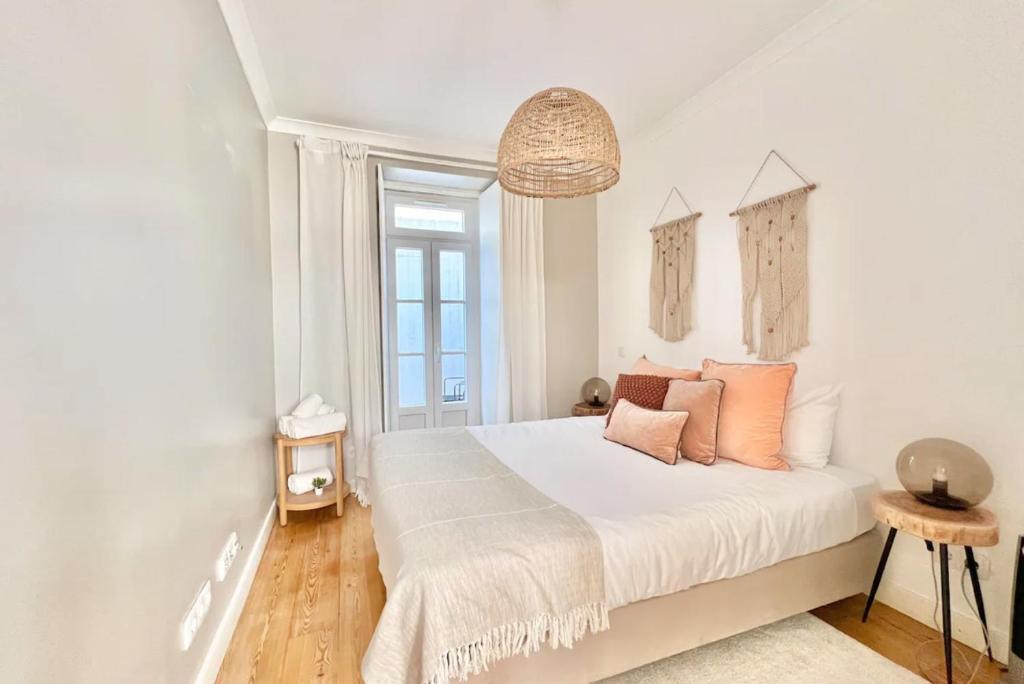 a white bedroom with a bed with orange pillows at Vila Rosário 3 studios with Patio by Homeful Homes in Lisbon