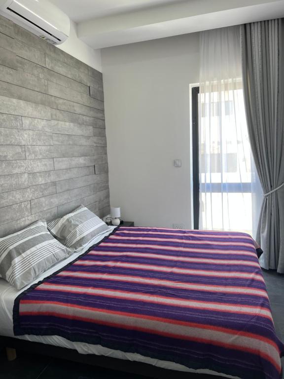 una camera da letto con un grande letto con una coperta a righe di Cosy & Modern Top Floor 1-bedroom Apartment a San Pawl il-Baħar