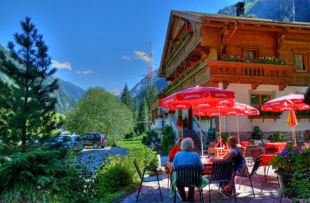 un grupo de personas sentadas en una mesa con sombrillas en Der Klaushof, en Mayrhofen