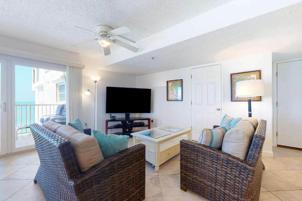 a living room with two chairs and a flat screen tv at Holiday Villas III 703 in Clearwater Beach