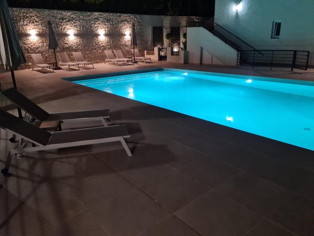 uma piscina à noite com cadeiras à volta em Daenerys - AzulenaCalpe em Calpe