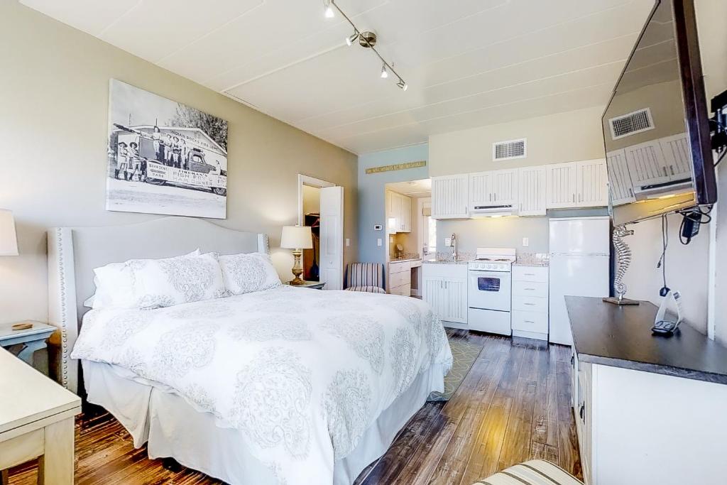 a bedroom with a white bed and a kitchen at Bungalow Beach Place 6 in Clearwater Beach