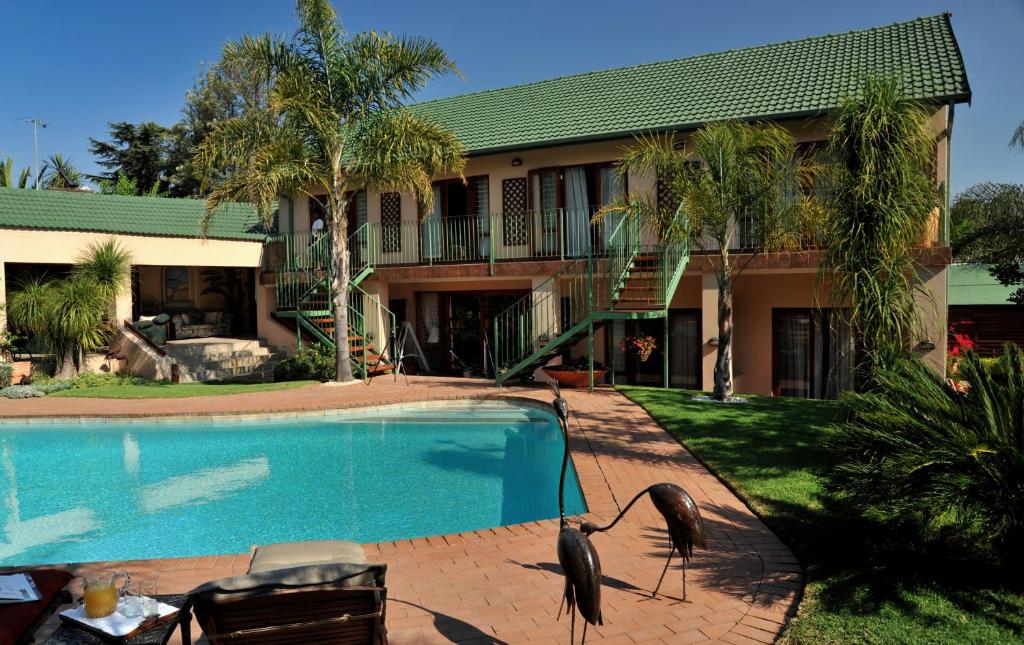 two birds standing by a swimming pool in front of a house at Claires of Sandton Luxury Guest House in Johannesburg