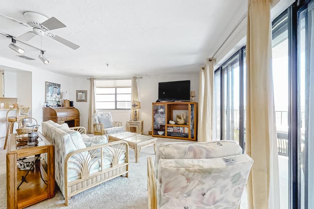 ein Wohnzimmer mit weißen Stühlen und einem TV in der Unterkunft Redington Place 201 in St Pete Beach