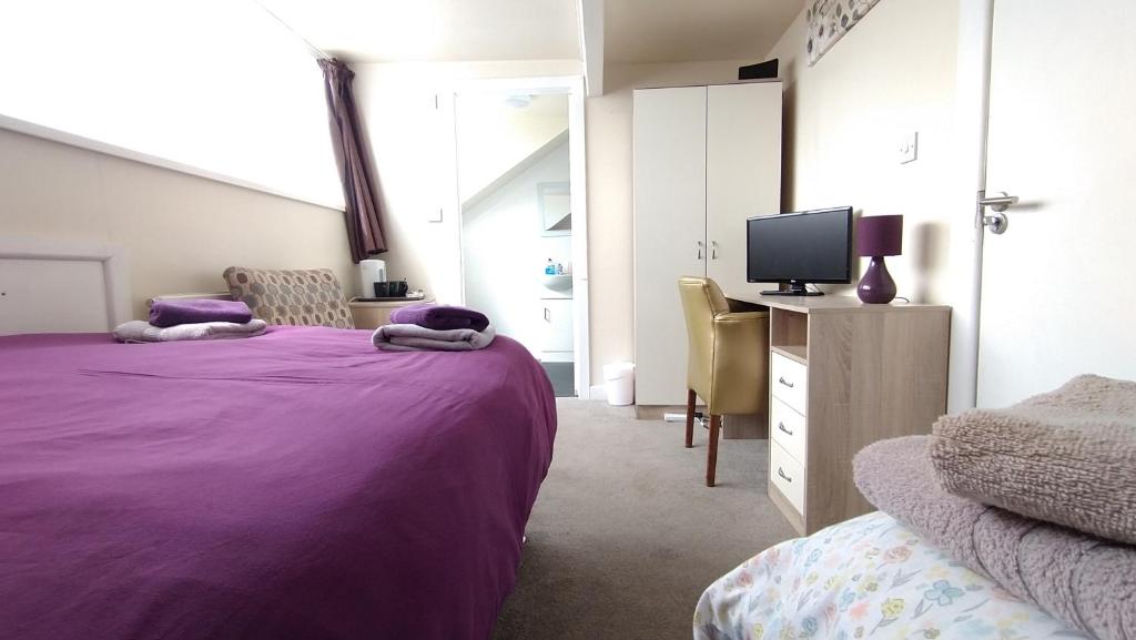 a bedroom with a purple bed and a tv at Shaftesbury Hotel in Blackpool