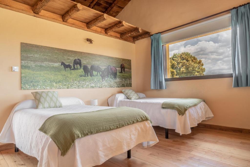 2 camas en una habitación con un cuadro en la pared en Eco-Lodge en la Reserva Privada Campanarios de Azaba - Proyecto de Conservación, en Espeja