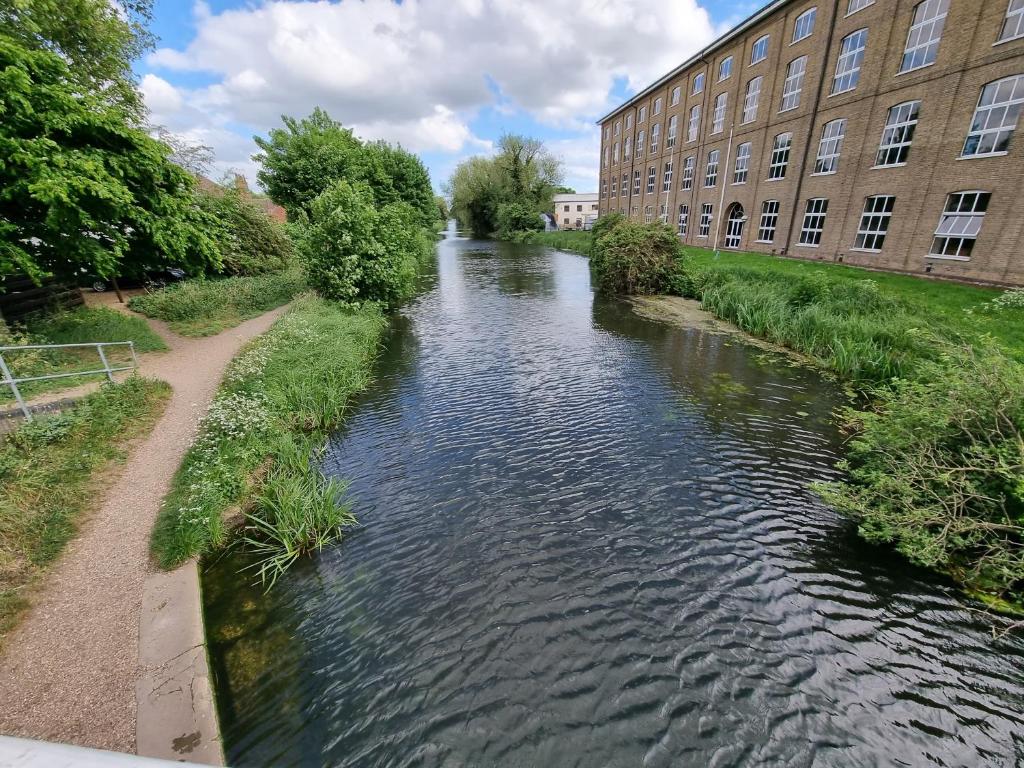 einem Fluss vor einem Gebäude neben einem Gebäude in der Unterkunft Swan Path Retreat - 2 Bedroom Apartment in Heybridge