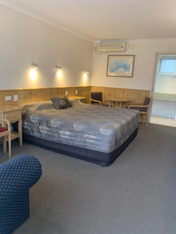 1 dormitorio con cama, escritorio y silla en LaTrobe Motel, en Morwell