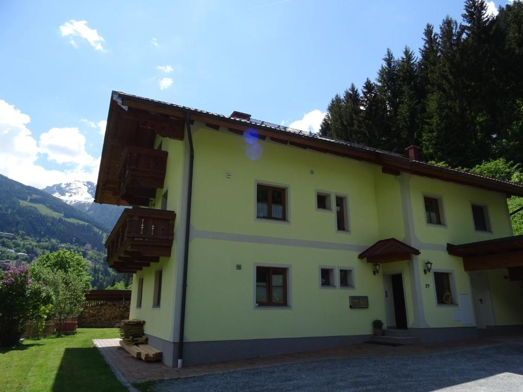 una casa gialla con finestre e montagne sullo sfondo di Appartement Klausner a Bad Gastein