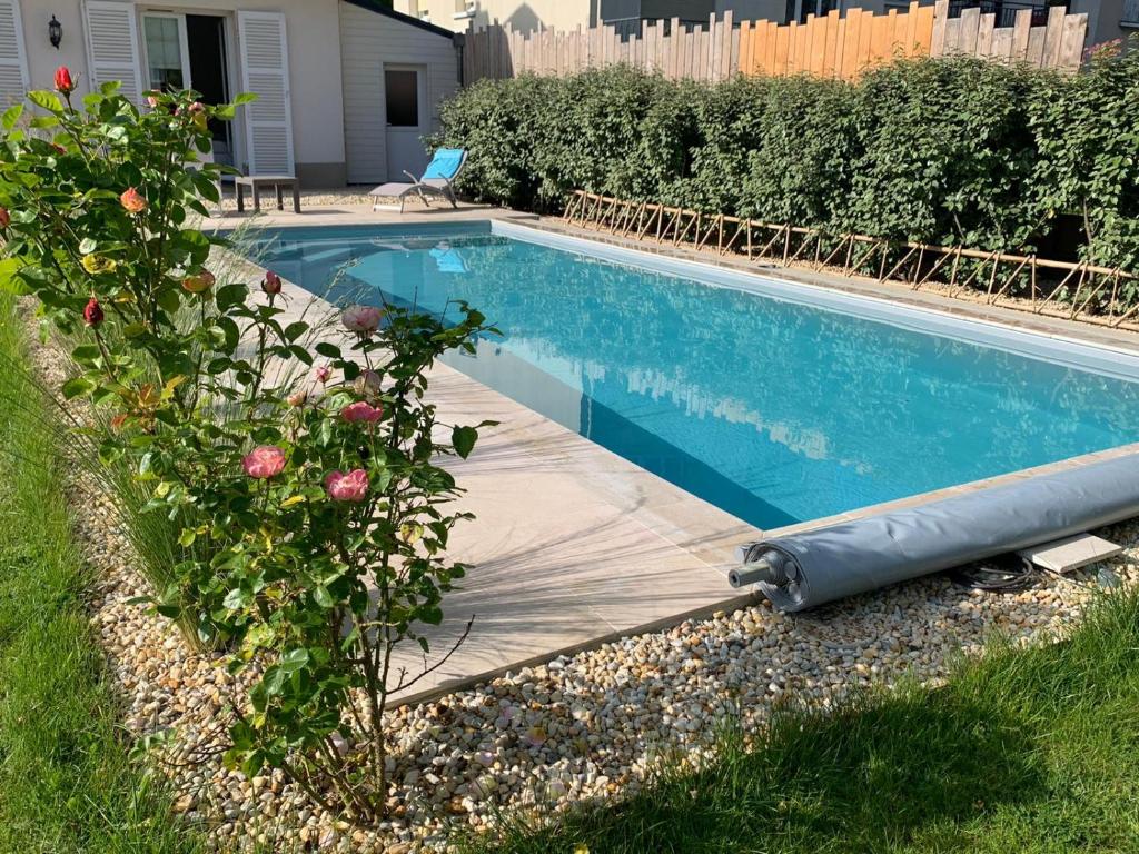 a swimming pool in a yard next to a house at Chambre d'hôtes de Verdigné Piscine chauffée Parking Wifi in Le Mans