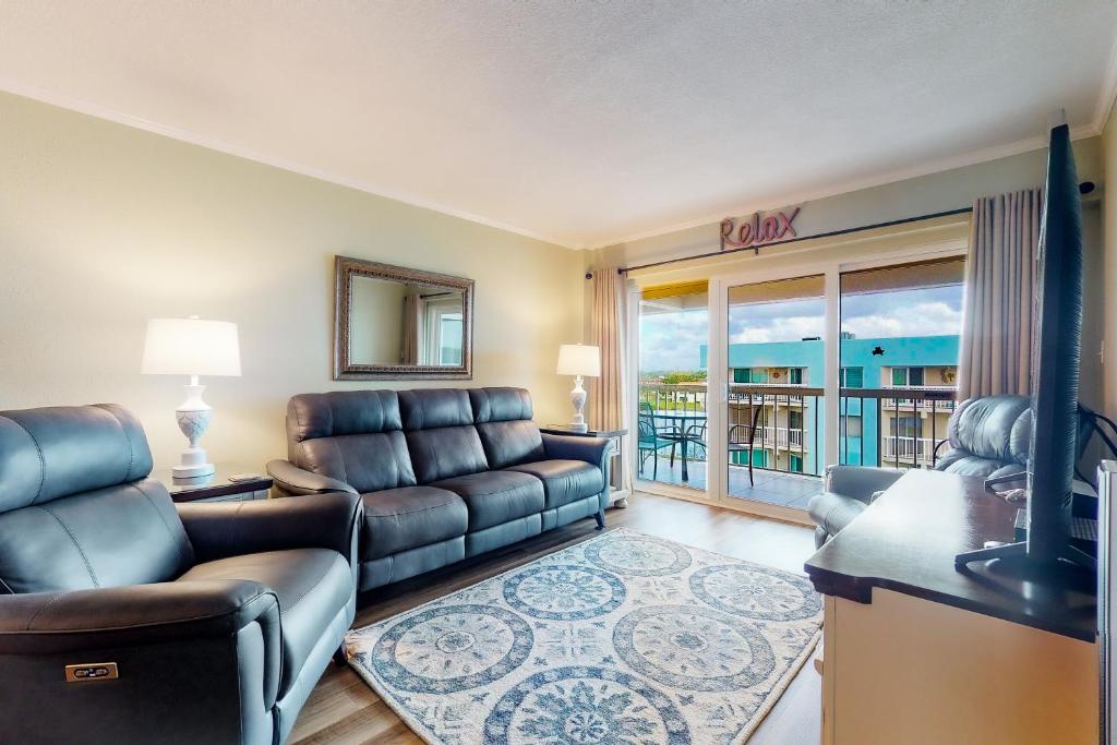 a living room with a couch and a television and a balcony at Water View 506 in Clearwater Beach