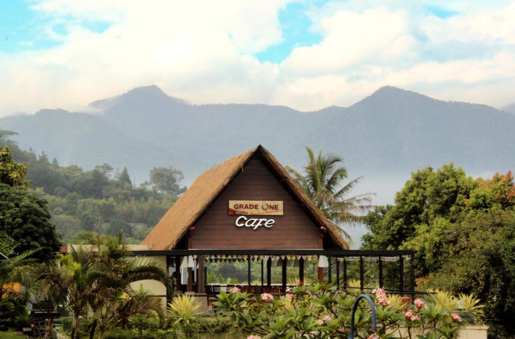 a building with a sign on it with mountains in the background at Alfa Resort Hotel and Conference in Puncak