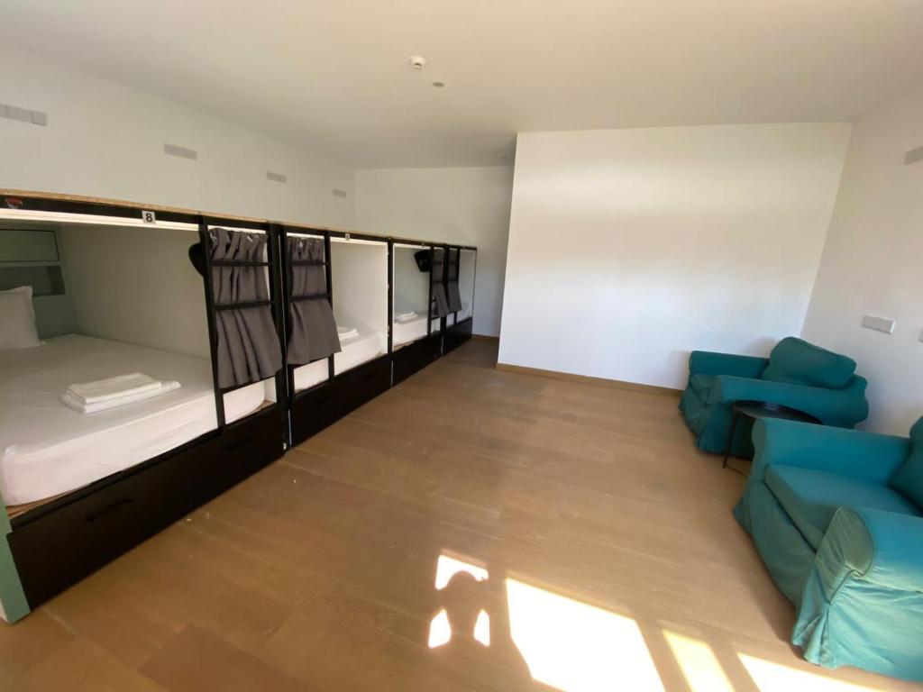 um quarto com três beliches e um sofá em Urban Habitat Capsule Beds em Nicósia
