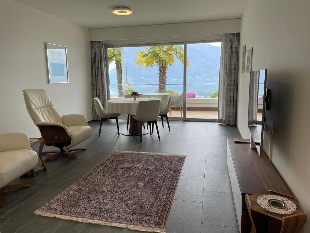 a living room with a table and chairs and a large window at Locarno-Monti: Solemonte Apt.103 in Locarno