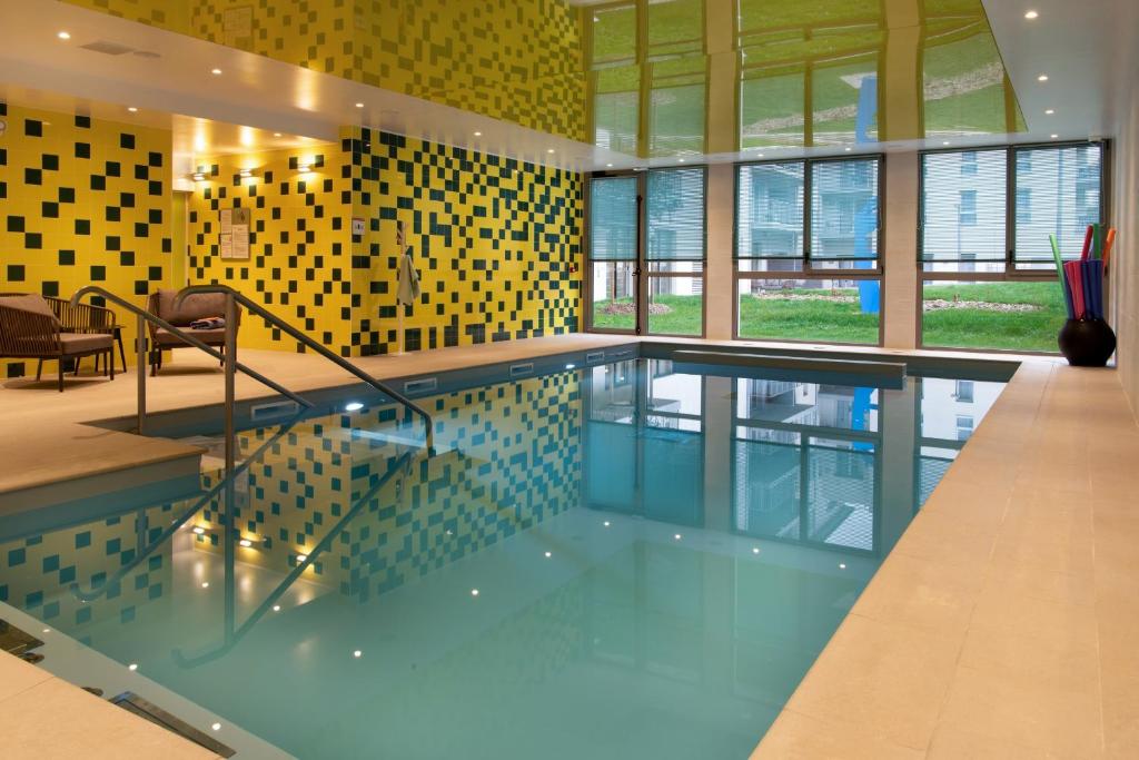 a swimming pool in a building with yellow tiles at DOMITYS La SARDONNE centre-ville in Le Puy en Velay