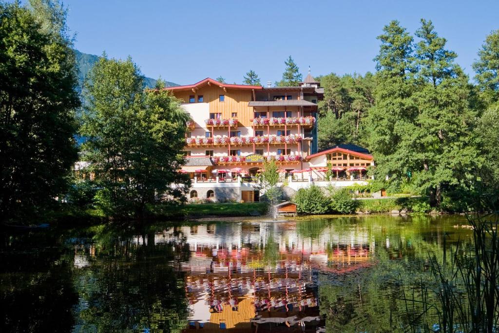 a hotel is reflected in the water of a lake at Huber Hotel Tramserhof in Landeck
