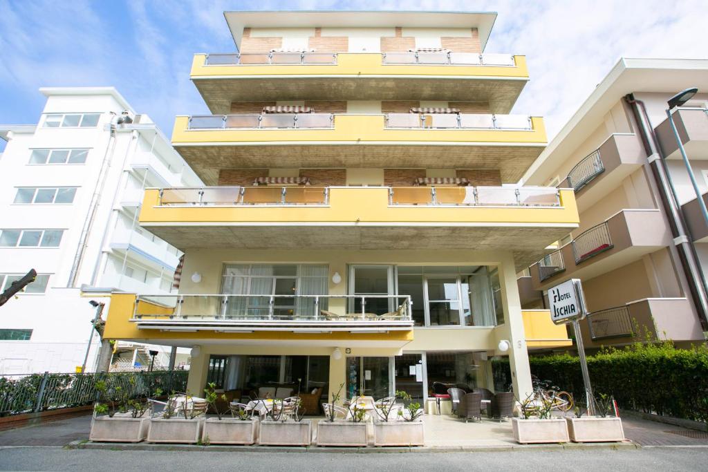 um grande edifício amarelo com mesas e cadeiras em Hotel Ischia em Rimini
