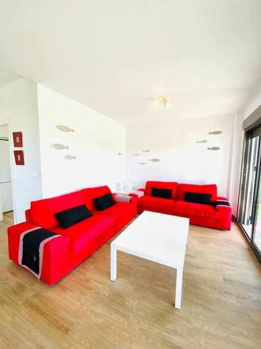 salon z 2 czerwonymi kanapami i białym stołem w obiekcie Chalets conilizate 12 pax piscina 300mts playa w mieście Conil de la Frontera