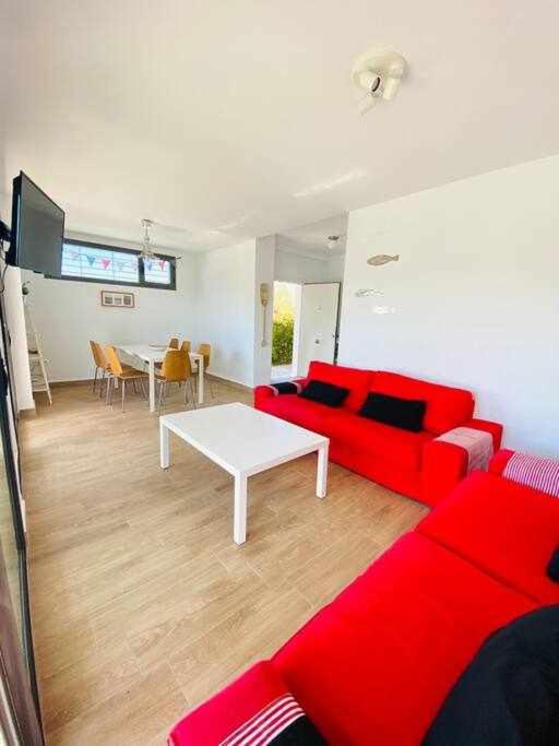 salon z czerwoną kanapą i stołem w obiekcie Chalets conilizate 12 pax piscina 300mts playa w mieście Conil de la Frontera