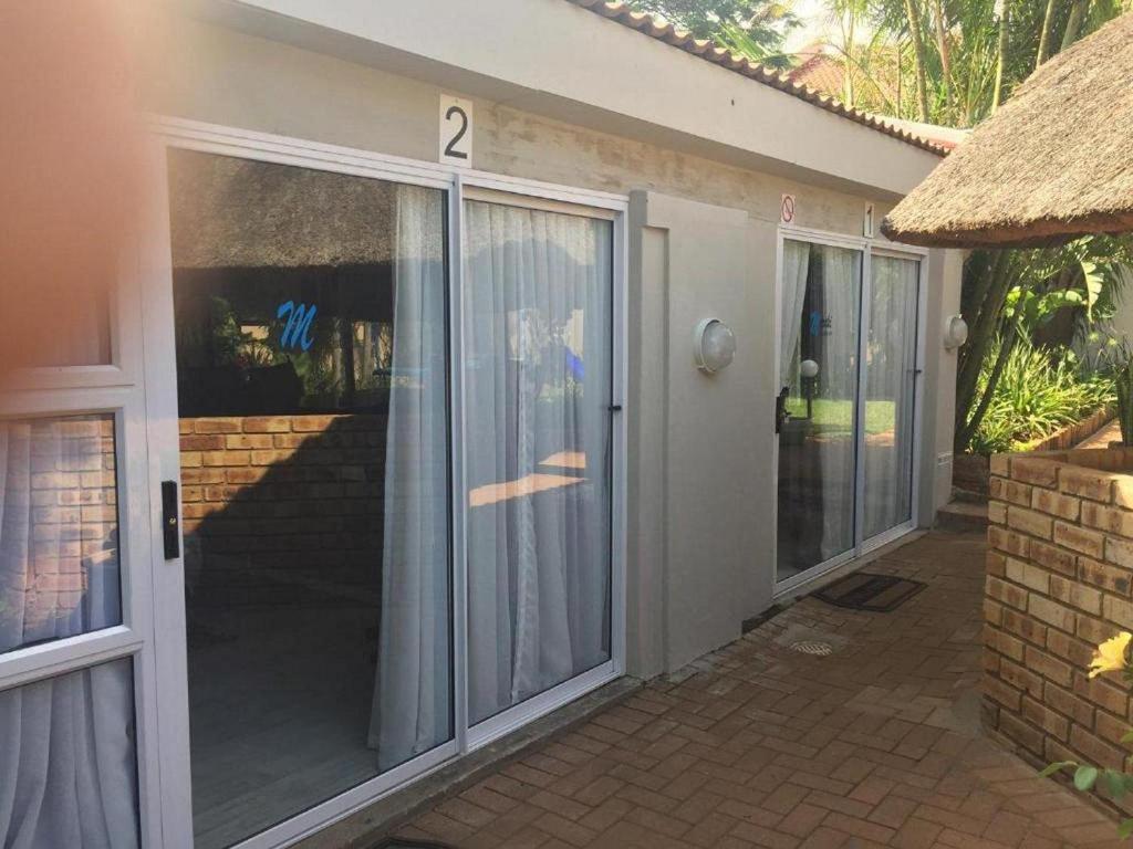 uma casa com portas de vidro deslizantes com o número dois em Meraki Upmarket Guesthouse em Rustenburg