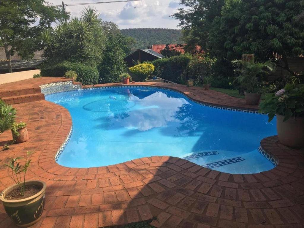 a large blue swimming pool on a brick patio at Meraki Upmarket Guesthouse in Rustenburg