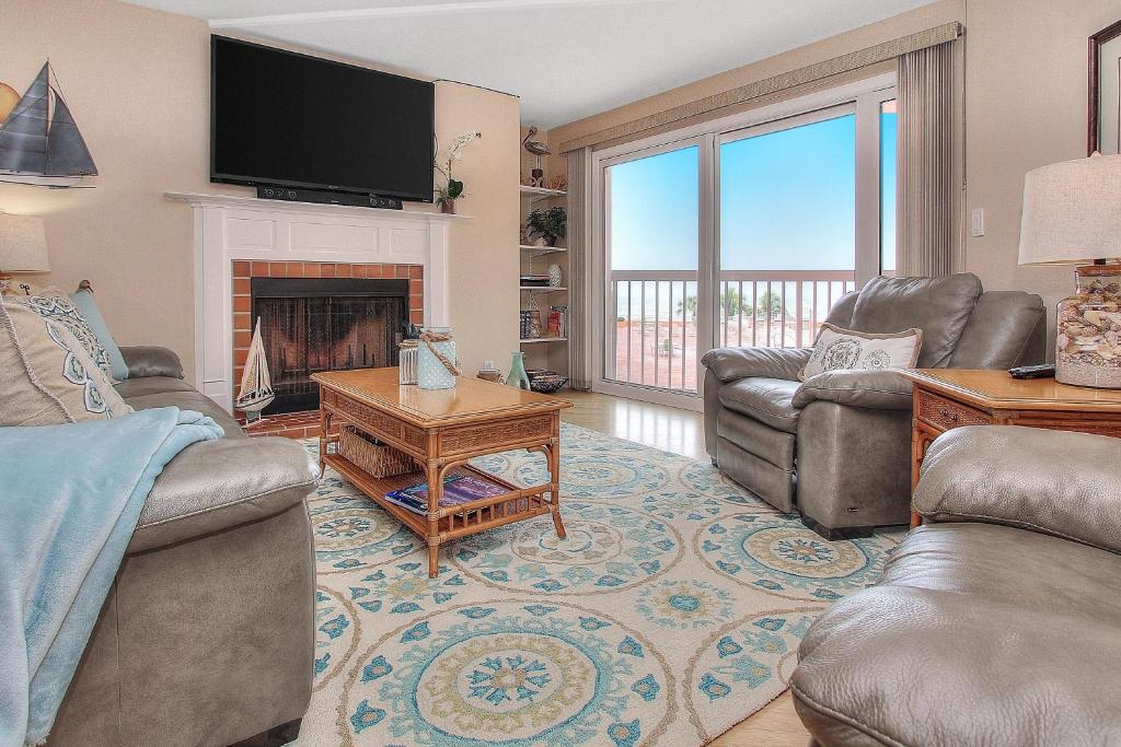 a living room with couches and a tv and a fireplace at Beach Cottage 2202 in Clearwater Beach
