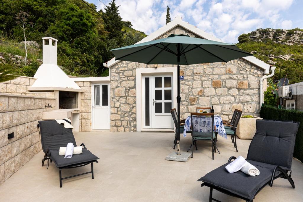 een patio met een parasol, stoelen en een tafel bij PERLA - small comfy house with the terrace in Prožura