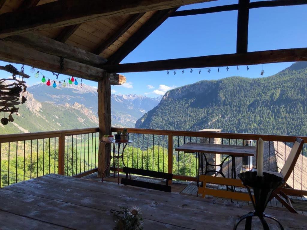 uma varanda com uma mesa e vista para as montanhas em maison immersion hautes alpes em Freissinieres