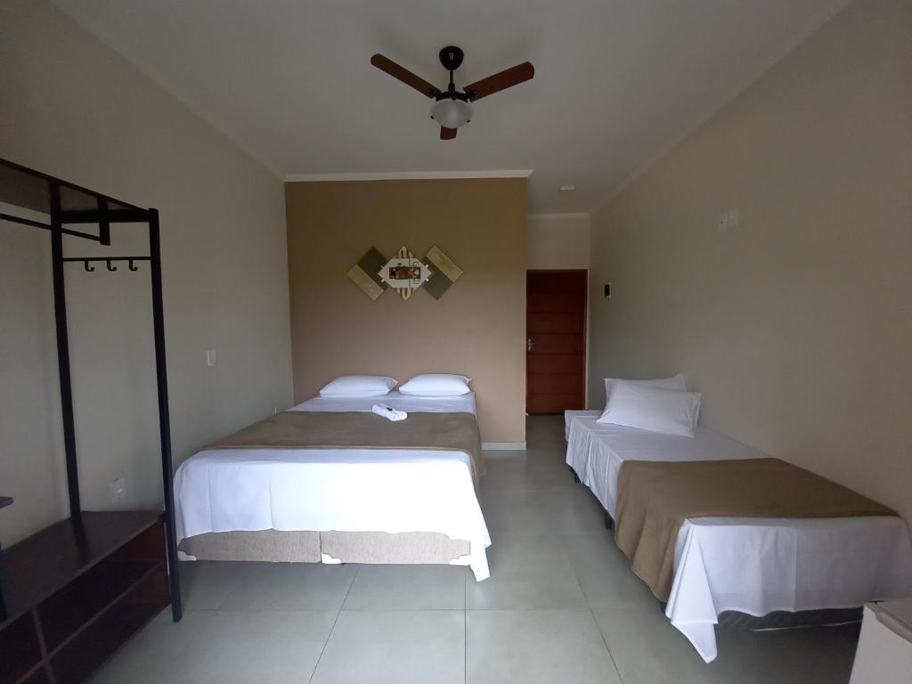 a bedroom with two beds and a ceiling fan at Chácara Vale Verde in Lindóia