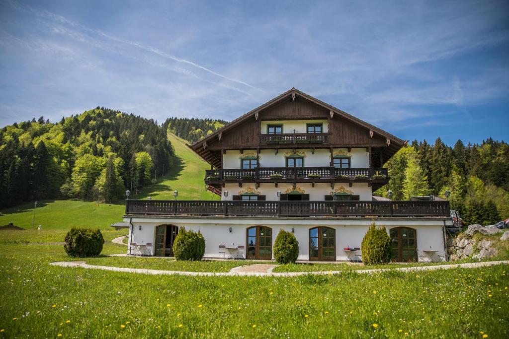 ein großes Haus auf einem Hügel mit grünem Feld in der Unterkunft Berghotel Sonnenbichl in Bad Wiessee
