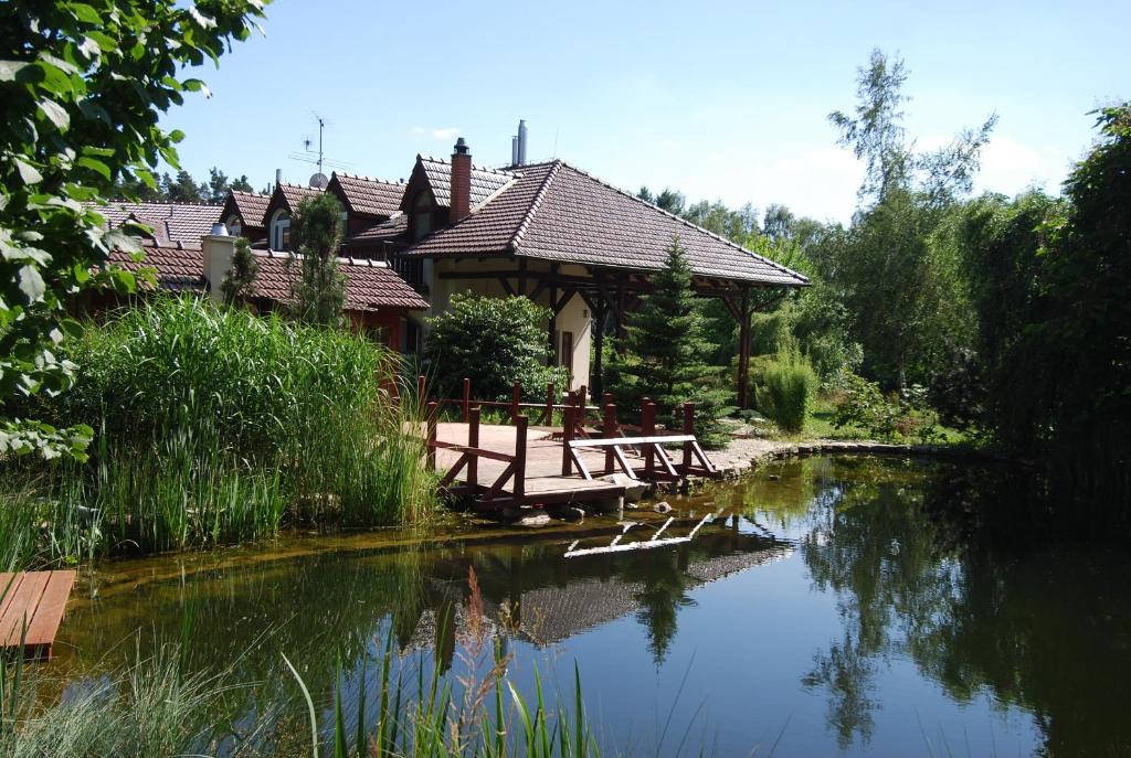 a house with tables and chairs next to a river at Ivanek guest house in Zvíkovské Podhradí