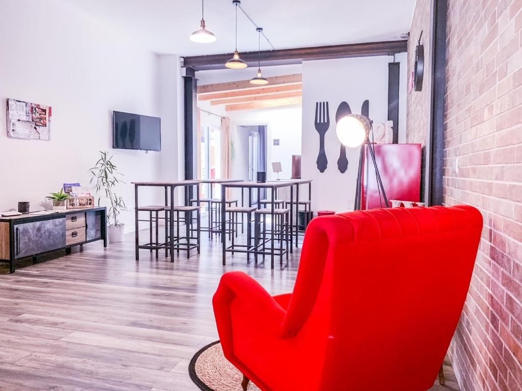 una sala de estar con una silla roja y mesas. en BB 26 Olbia, en Olbia