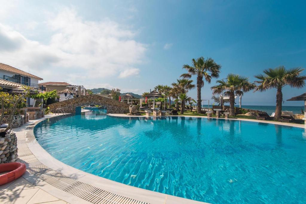 duży basen z palmami i oceanem w obiekcie Mirage Arillas Studio Type C18 w mieście Arillas