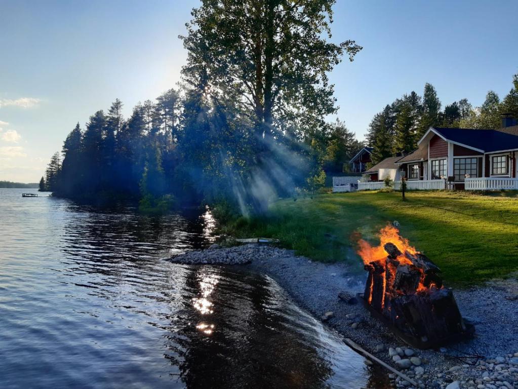 a bonfire on the shore of a lake at Lentiira Holiday Village in Lentiira