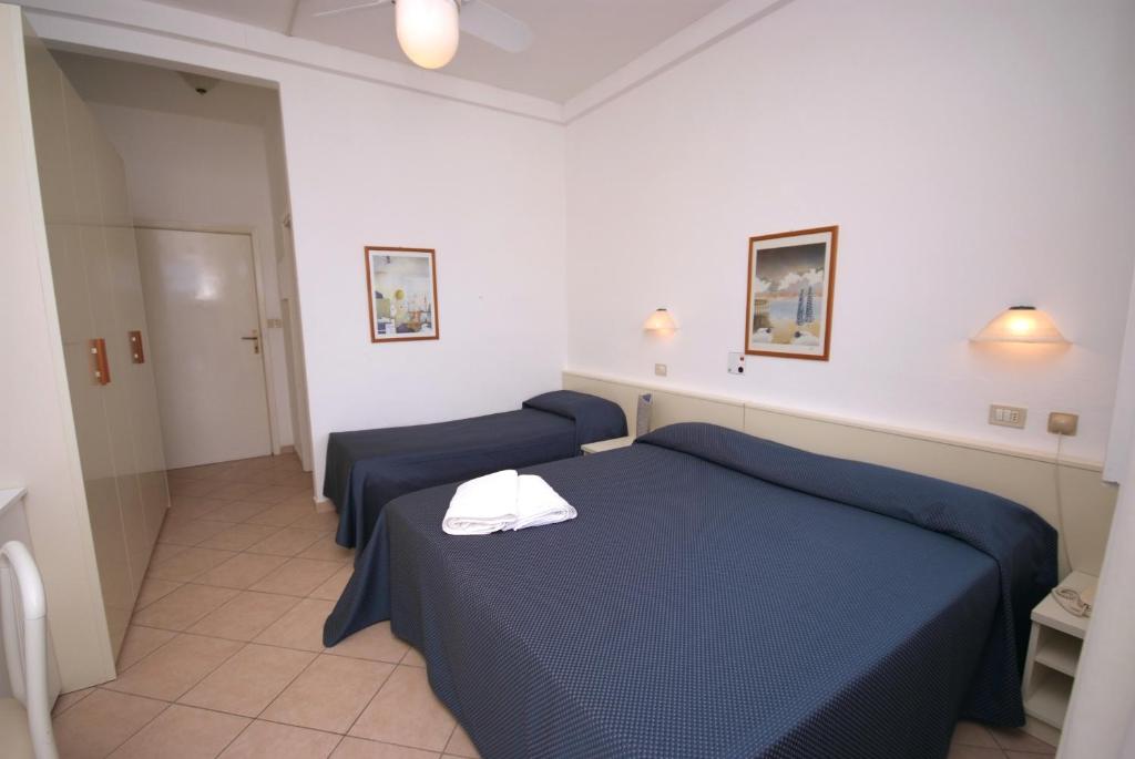 a bedroom with two blue beds and a hallway at Hotel Dino in Capoliveri
