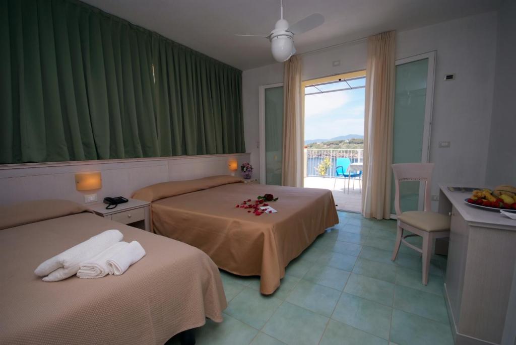 a hotel room with two beds and a balcony at Hotel Dino in Capoliveri