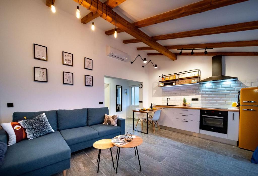 uma sala de estar com um sofá azul e uma cozinha em Novouređeni apartman Marko em Mundanije