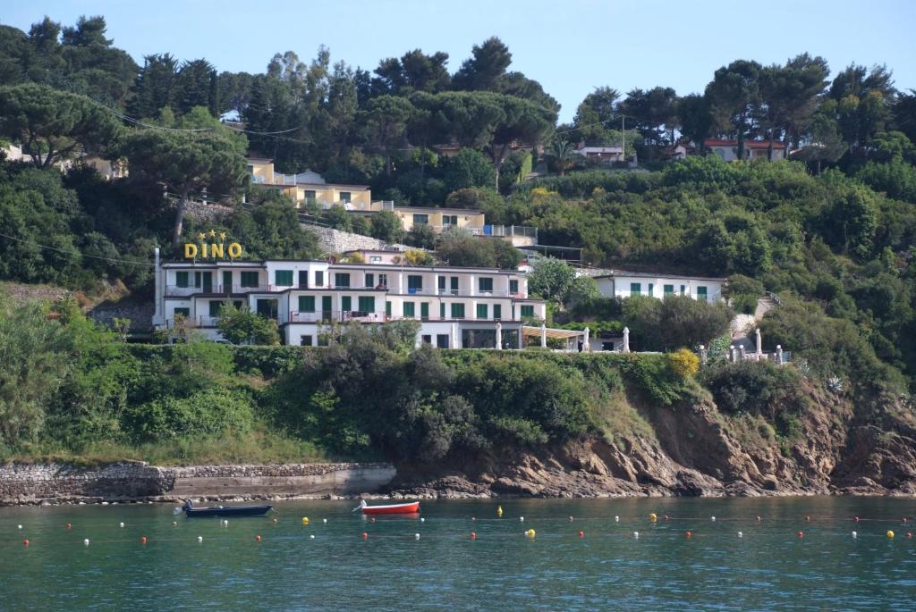 a building on a hill next to the water at Hotel Dino in Capoliveri